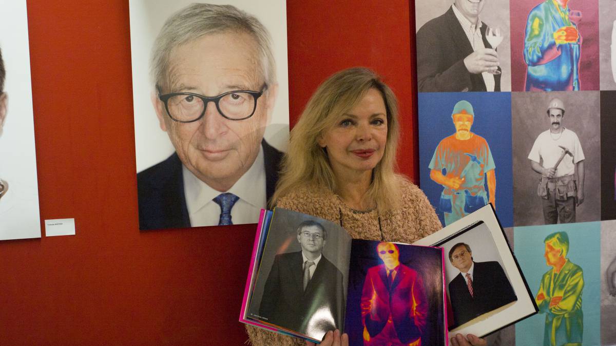 Marita Ruiter, directora de la galería Clairefontaine de Luxemburgo, junto a varios retratos de Jean-Claude Juncker.