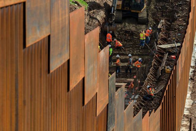Trabajadores levantando una valla en la frontera de México con Estados Unidos.