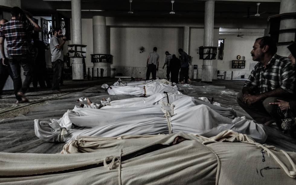 Cuerpos de niños y adultos cubiertos por sudarios tras un ataque con gas nervioso en Guta.