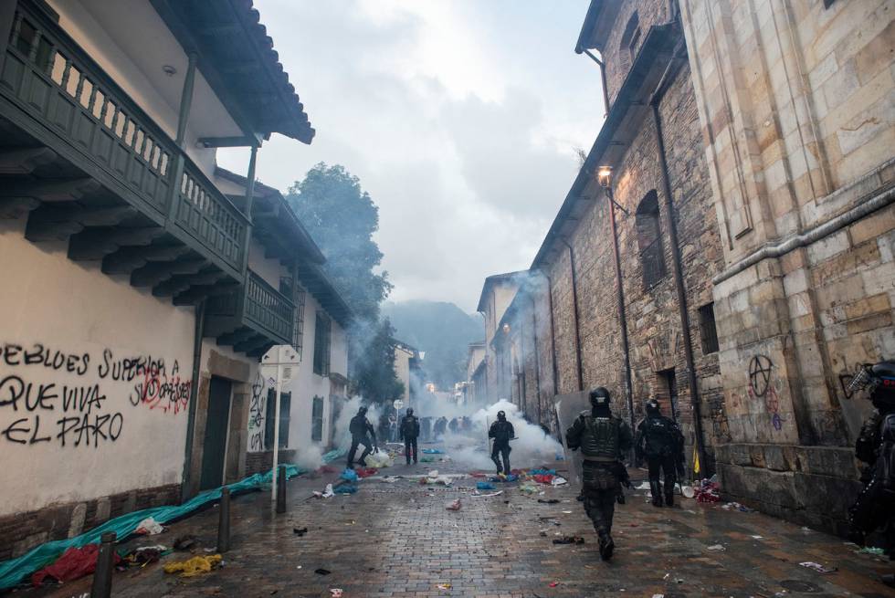 Integrantes del Escuadrón Móvil Antidisturbios lanzan gases y caminan entre escombros después de los enfrentamientos en la Plaza Bolívar cuando unos encapuchados intentaron ingresar a la Alcaldía de Bogotá.