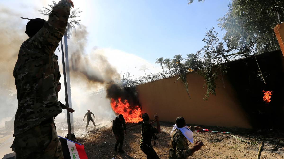 Un grupo de milicianos prende fuego este martes al muro de las instalaciones de la Embajada de EE UU en Bagdad.