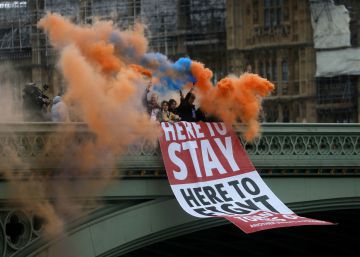Un grupo de personas sostiene bengalas de humo mientras coloca una pancarta en el puente de Westminster, en Londres, este viernes.