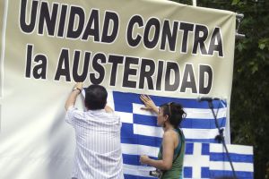 Dues persones col·loquen una bandera de Grècia durant una concentració a Madrid convocada en suport al poble grec.