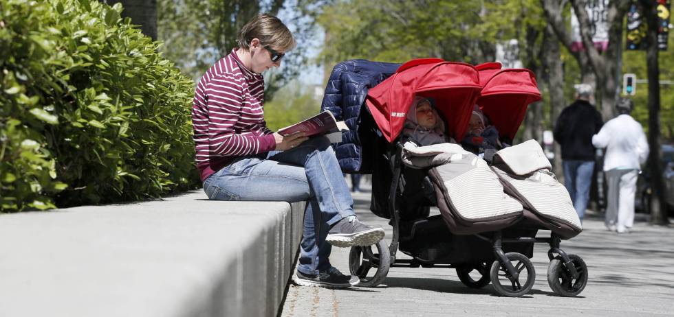 Una madre múltiple con su carrito gemelar en Madrid.