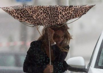 Una mujer sujeta el paraguas intentando que no se le vuele debido al viento y a la lluvia en Málaga.