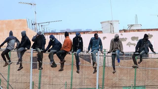Inmigrantes encaramados en la valla de Melilla.