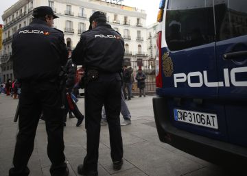 Dos agentes de la Policía Nacional, de pie, junto a un furgón.