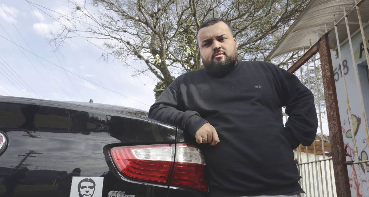 Anriel do Prado Neves, de 24 anos, mostra o adesivo de Jair Bolsonaro no carro que dirige para um aplicativo.