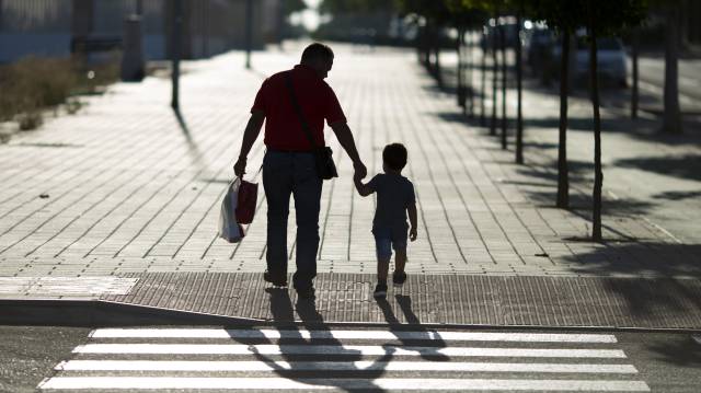 Un hombre lleva a su hijo al colegio, en una fotografía de archivo.