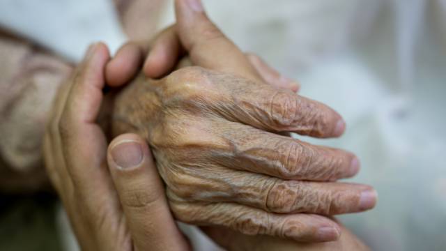 Una persona da la mano a un anciano.