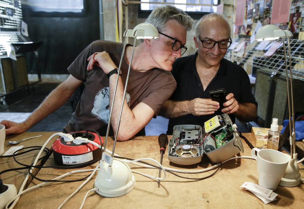 El reparador José Manuel Gutiérrez (derecha) junto a José Ramón Martín, otro voluntario, arreglan un radiocasete el pasado sábado en el Repair Café de MediaLab-Prado, en Atocha (Madrid).