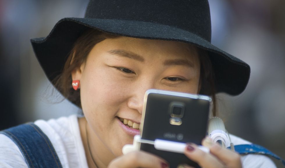 Una turista asiática mira su teléfono móvil. 