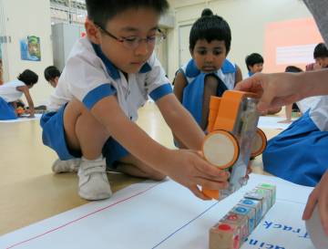 Un alumno de preescolar juega con Kibo, un juguete robotizado.