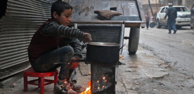Un niño cocina en la calle en la zona asediada de la ciudad de Alepo Un niño cocina en la calle en la zona asediada de la ciudad de Alepo