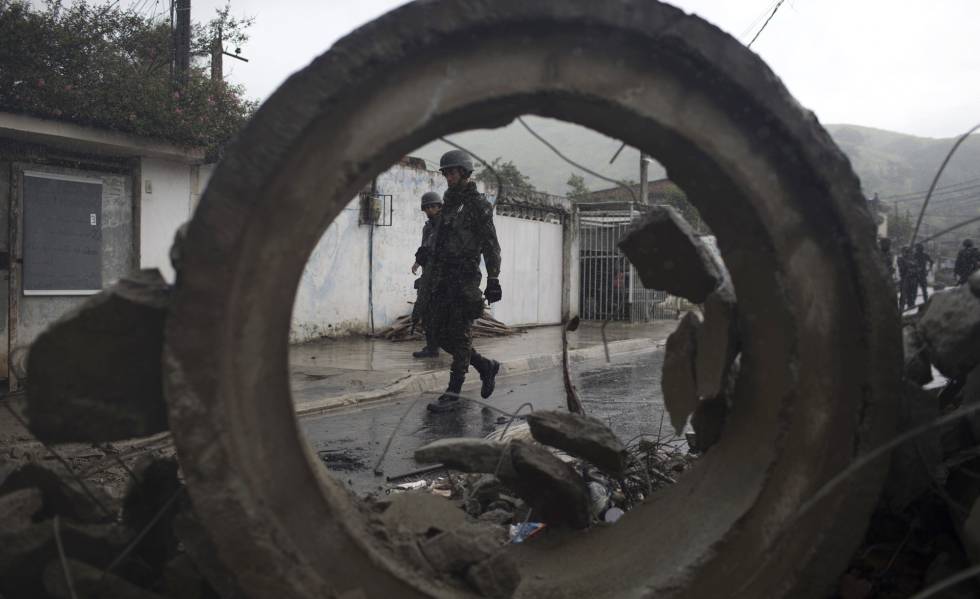 Soldados passam por barricada durante operação surpresa na favela da Coreia, no Rio de Janeiro.