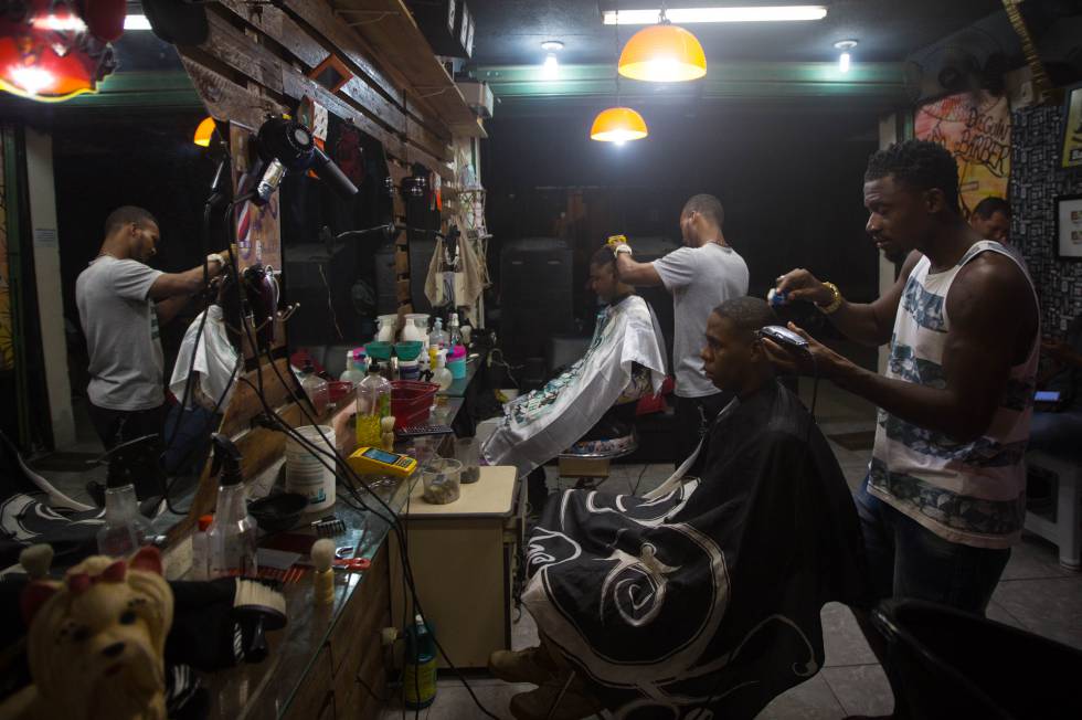 Sagat corta o cabelo de um cliente em sua barbearia, na favela da Mangueira.