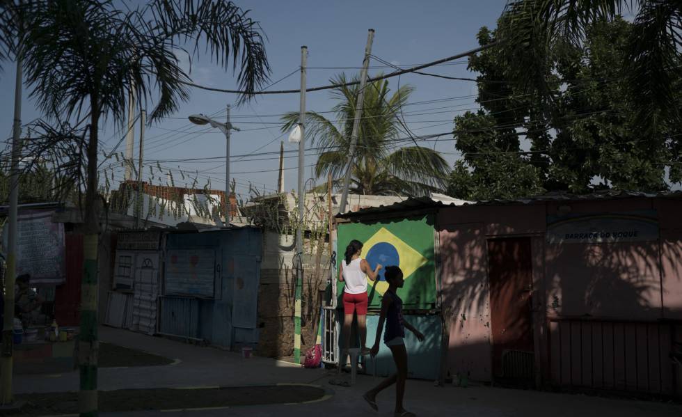 Moradora do Complexo do AlemÃ£o, no Rio de Janeiro, pinta a bandeira do Brasil numa parede.