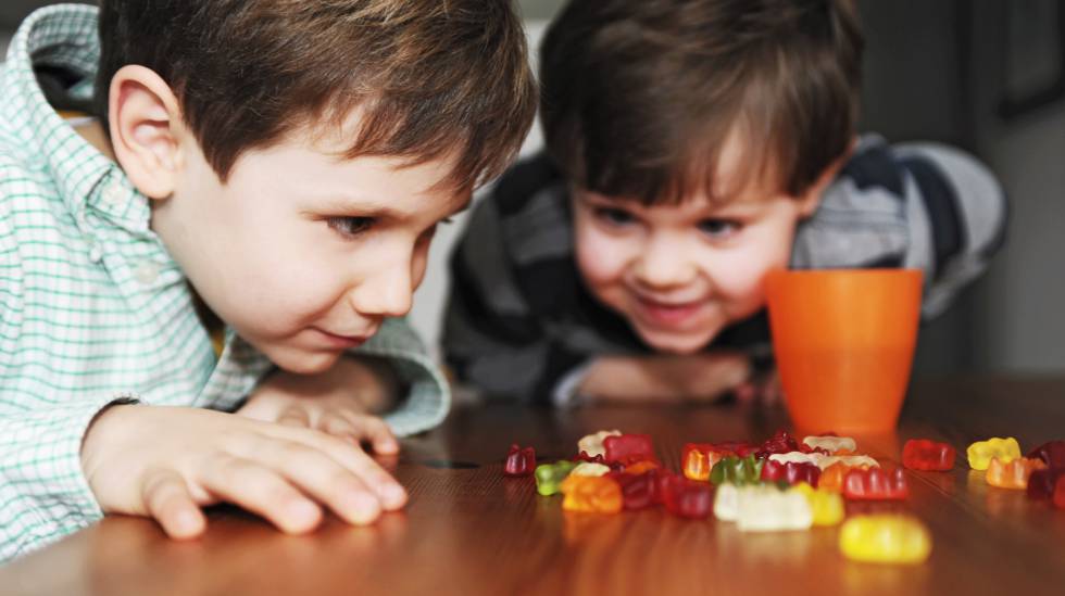 Duas crianças olhando ansiosas para doces. 