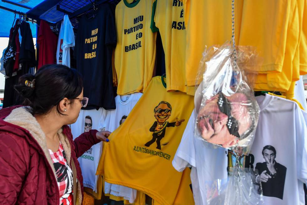 Mulher olha camiseta com a imagem do candidato Jair Bolsonaro em shopping popular no centro de São Paulo. 