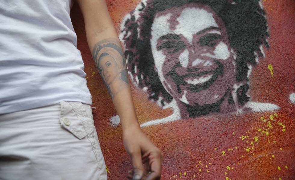 A viÃºva de Marielle Franco, MÃ´nica BenÃ­cio, ao lado de grafite da vereadora assassinada.