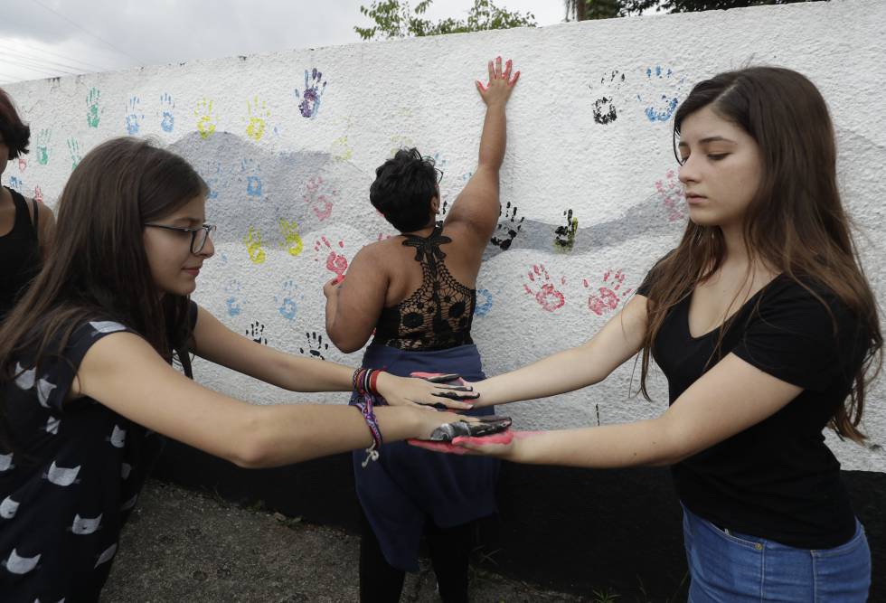 Alunas colocam suas impressões digitais em uma parede na Escola Estadual Raul Brasil, palco de um massacre praticado por dois ex-alunos.