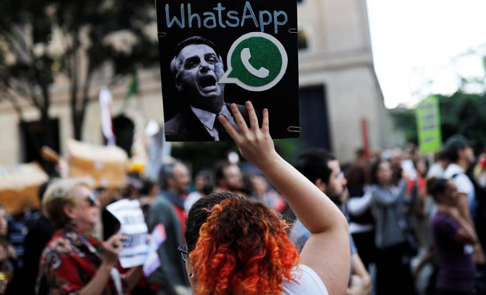 Uma mulher segura um cartaz, durante um protesto em São Paulo, contra suposto disparo em massa de notícias falsas em favor de Jair Bolsonaro.