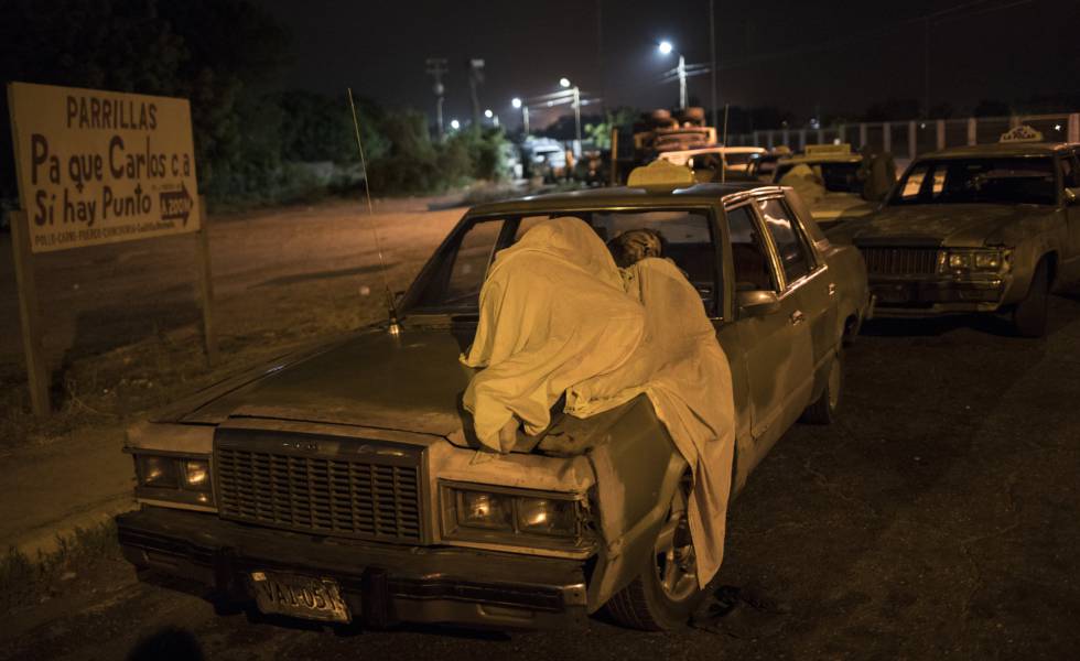 Um homem dorme sobre seu carro enquanto espera por gasolina em Maracaibo.