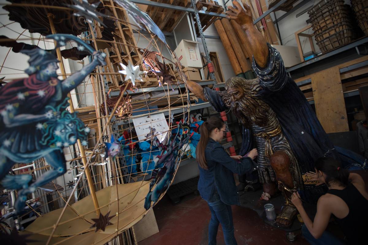 Dos personas dan las &uacute;ltimas pinceladas a una estatua de Atlas, este jueves durante los preparativos del desfile Fiesta Barroca