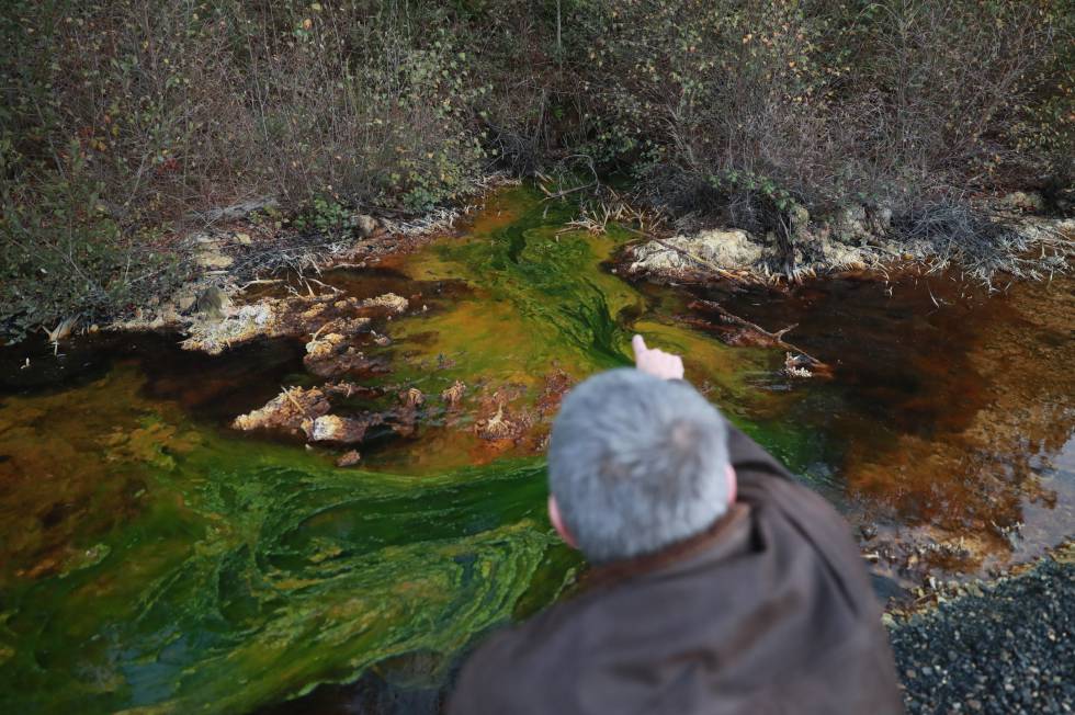 Un vecino de Touro muestra el drenaje ácido de mina en el agua de la zona.