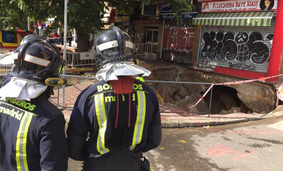 Dos bomberos observan el socavÃ³n de la avenida del MarquÃ©s de Corbera.