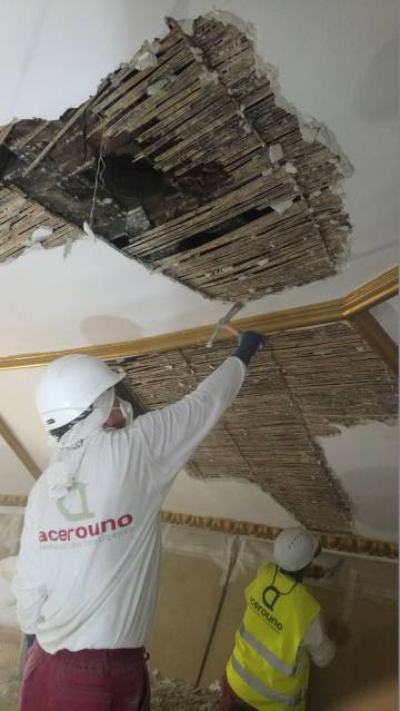 Dos trabajadores eliminan el falso techo y sacan a la luz el artesonado de la iglesia de Santa MarÃa la Blanca, en Canillejas.