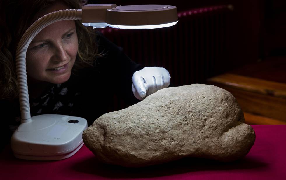 La investigadora Ines Domingo junto a la piedra paleolítica con la escena de grullas y humjanos. 