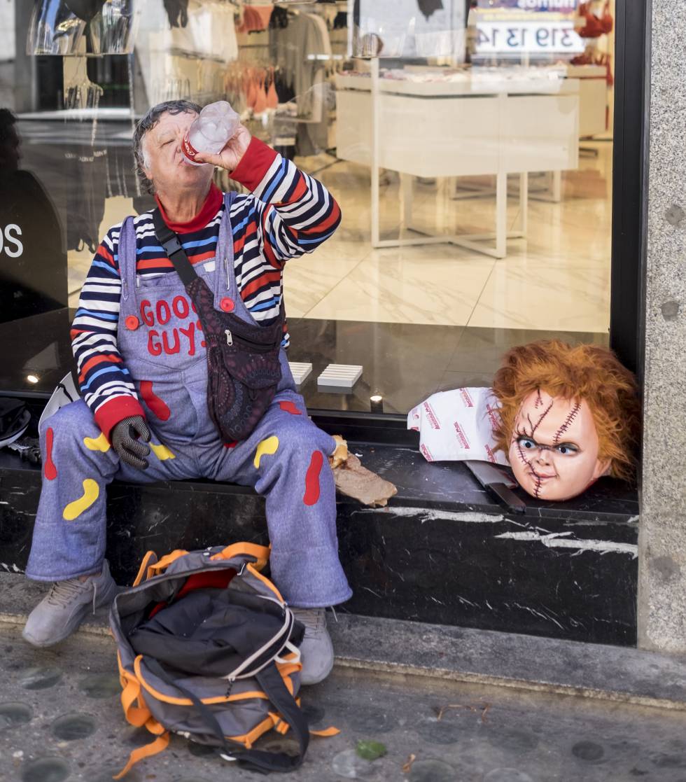 Juan, dressed as Chucky, takes a rest in front of a shop.