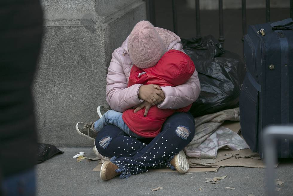 Una madre con su hijo demandantes de asilo esperan alojamiento a las puertas del Samur Social este lunes.