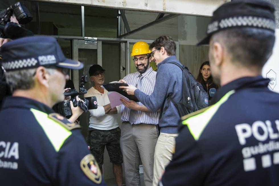 Los dos socios de Haibu 4.0., Eduardo Jausi (alias Eddie Wattenwil), con gorra negra; y Marc Olivé, con casco amarillo, durante el precinto de su piso colmena por parte de la Guardia Urbana de Barcelona, el 22 de octubre de 2018.