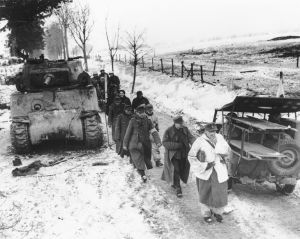 Prisioneros alemanes pasan junto a un Sherman y un jeep Willys durante la batalla de las Ardenas.
