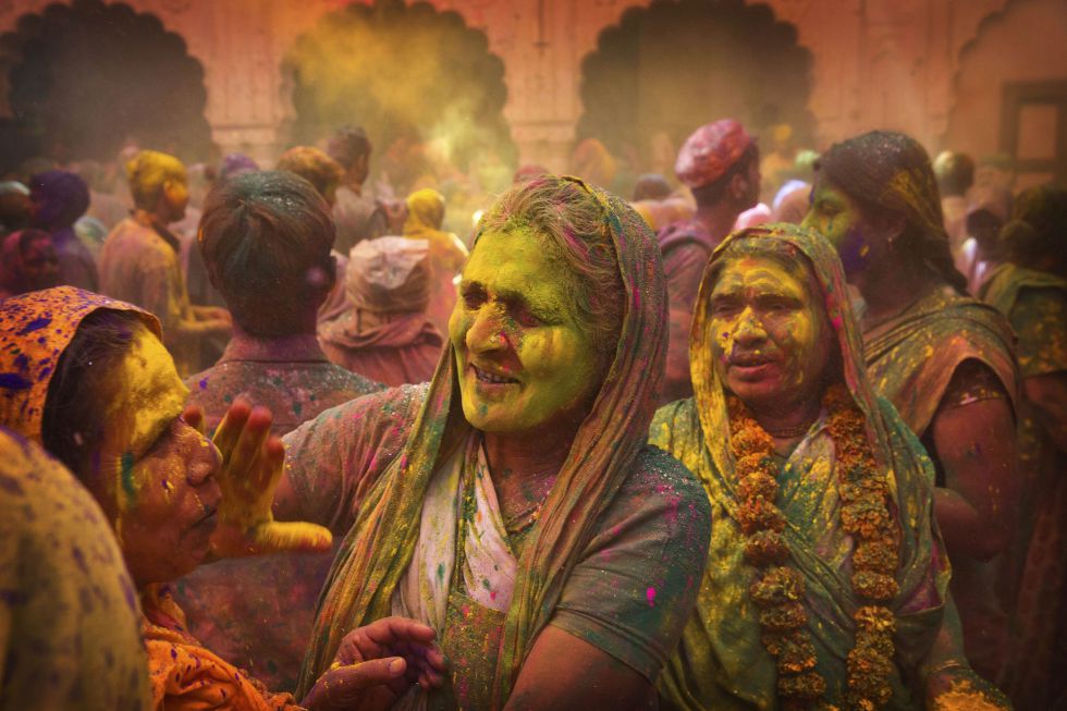Viudas hindús se pintan la cara con polvos de colores en el templo Gopinath.