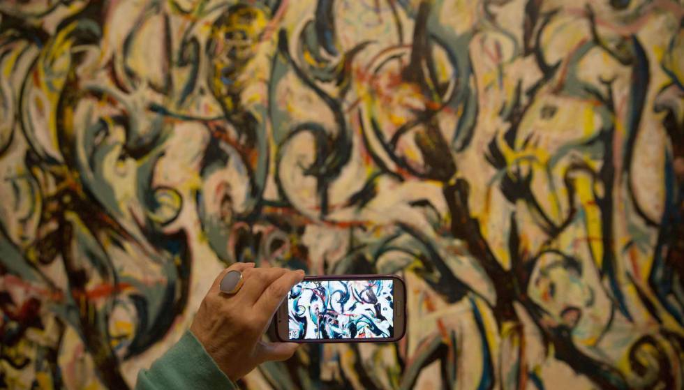 Un visitante toma una foto de la pintura 'Mural' (1943) de Jackson Pollock en la exhibición de la Royal Academy londinense.