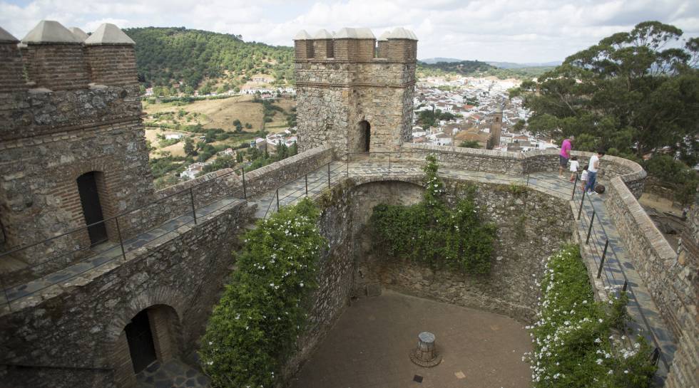 Una familia visita el castillo de Cortegana, con la población al fondo y Portugal en el horizonte.