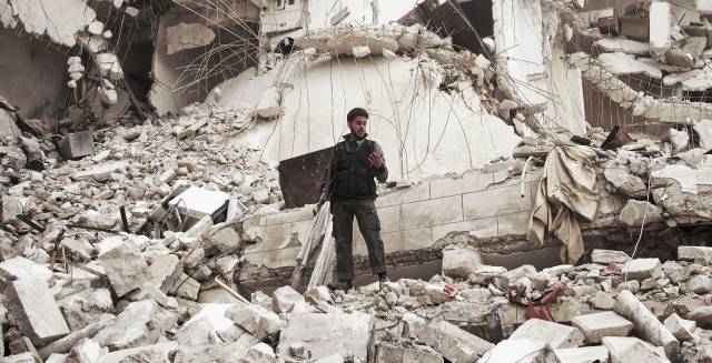 Un miliciano rebelde, entre las ruinas de un edificio en Aleppo (Siria).
