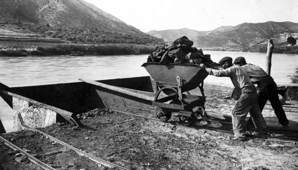 Unos trabajadores cargan un barco de carbón en el río Ebro en los alrededores de Mequinenza a principios del siglo XX.