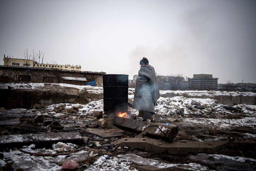 Un inmigrante se calienta  junto a una hoguera en Belgrado.