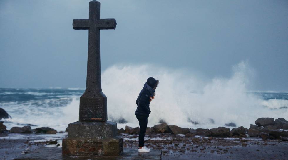 Una mujer junto a una cruz en la costa del desembarco de NormandÃ­a.