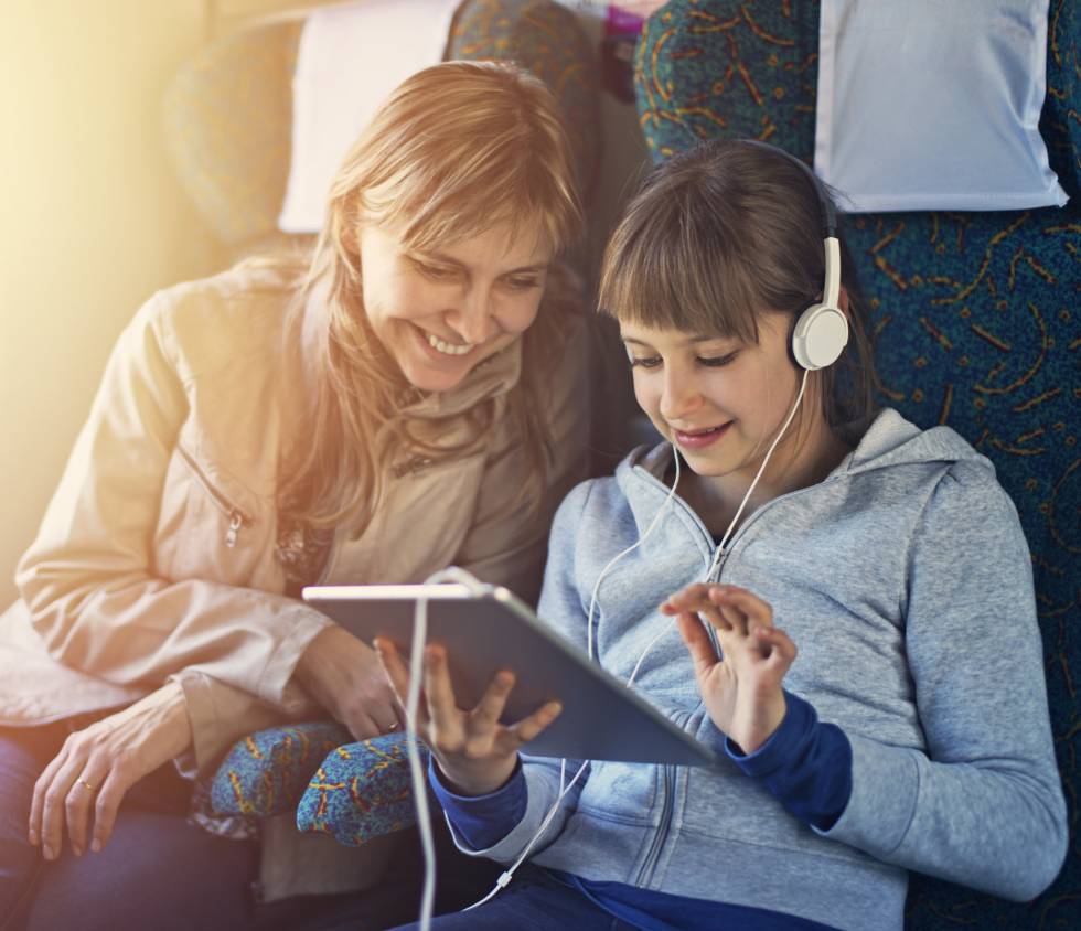 Una madre y una hija disfrutan de contenidos en su tableta, en un tren.