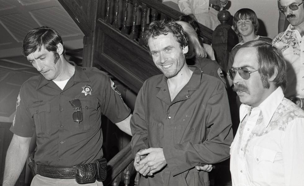 El asesino de mujeres Ted Bundy, en el centro, sale escoltado tras una sesión de su juicio en 1977.