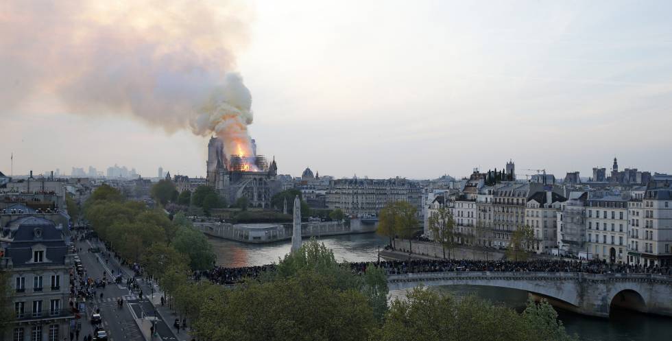 Centenas de pessoas contemplam o avanço das chamas em uma ponte sobre o Sena.