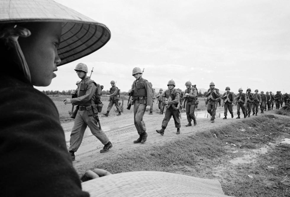 Una vietnamita observa pasar una columna de soldados estadounidenses.