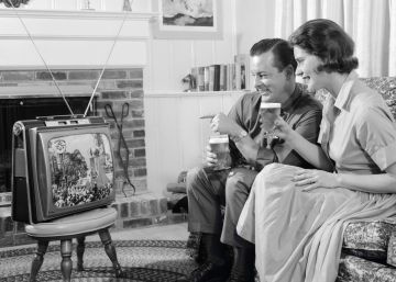 Una pareja mira su televisión portátil en una fotografía tomada en los años sesenta. 