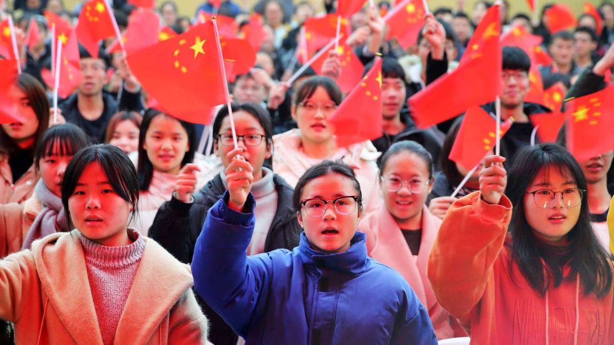 Varios estudiantes de una universidad de la provincia de Anhui ondean banderas de China, en 2018.