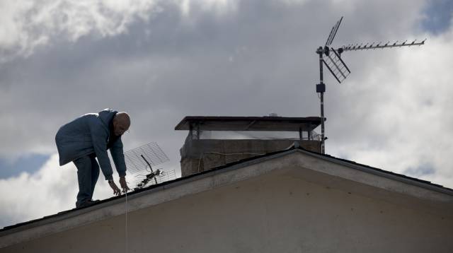 Un antenista cambia una antena antigua en Madrid.